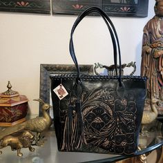 Art With Leather Black Handmade Tassled Floral Tooled Handbag. Measures Approximately 16" 12" Handles 12" Drop.Pre-Owned Brand New Never Used .Please See The Photos. Traditional Black Rectangular Shoulder Bag, Traditional Black Rectangular Bag, Traditional Black Tote Shoulder Bag, Traditional Black Tote Bag, Artisan Black Tote Bag, Traditional Black Bag For Everyday Use, Black Hand Tooled Tote Bag, Black Hand Tooled Bags For Everyday Use, Black Hand Tooled Tote Shoulder Bag