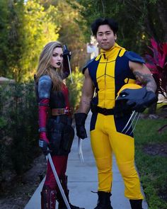 two people dressed as wolverine and deadpool standing next to each other on a sidewalk