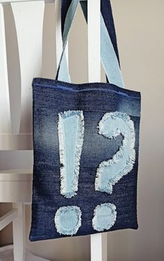 a denim tote bag with the letter s on it hanging from a white chair