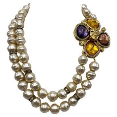 This vintage 1980s Robert Goosens for Yves Saint Laurent pearl necklace is a stunning piece of jewelry. The two strand design adds dimension and elegance to the piece, while the poured resin flower clasp is a statement feature. The large flower clasp, measuring 3 inches, is adorned with clear gold, purple, and plum poured resin stones, adding a pop of color and sparkle. The faux Baroque glass center pearls, each measuring 0.5 inches in diameter, are accented with rhinestone rondelles, adding a touch of glamour to the necklace. The wearable length of the necklace is 21 inches, with the shortest strand measuring 17 inches and the longest strand measuring 21 inches. Overall, this necklace is a beautiful example of vintage Yves Saint Laurent jewelry and would make a striking addition to any co Smokey Topaz, Citrine Stone, Color Dorado, Multi Strand Necklace, Topaz Gemstone, Fashion Jewellery, Glass Necklace, Strand Necklace, Hermes Birkin