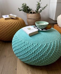 three knitted poufles sitting on the floor in front of a window with books