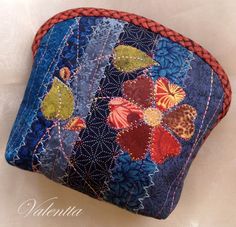 a close up of a small purse on a white surface with an embroidered flower design