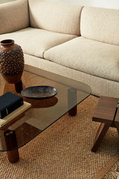 a glass coffee table sitting on top of a rug in front of a white couch