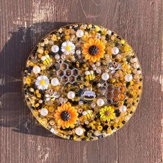 a glass plate with flowers and bees on it sitting on top of a wooden table