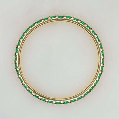 a green and white beaded bang bracelet on a white surface with gold clasps