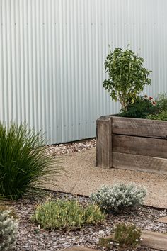 a wooden bench sitting in the middle of a gravel area next to a planter