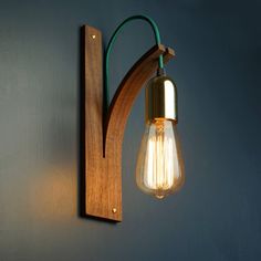 a light that is on the wall next to a wooden bracket with a light bulb hanging from it