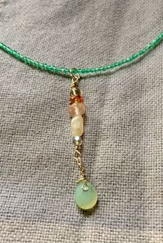 This choker necklace is 14 inches of green quartz, with accents of amethyst, rose quartz, mother of pearl, and chalcedony.  The findings are Sterling silver, and the drop is 2 inches.  The necklace lays high on the neckline, just at the collar bones, but the drop of 2 inches makes this very dramatic.  Shipping in the US is free.  I donate a portion of my proceeds to charity. Green Gemstone Dangle Earrings, Elegant Wire Wrapped Necklaces, Dangle Gemstone Jewelry For Meditation, Unique Briolette Necklace With Natural Stones, Bohemian Green Jewelry With Gemstone Accents, Unique Briolette Natural Stones Necklace, Adjustable Spiritual Necklace With Gemstone Accents, Spiritual Green Onyx Necklace With Gemstone Beads, Spiritual Adjustable Necklace With Gemstone Accents