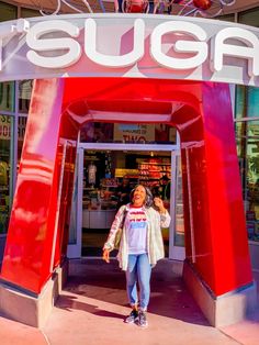 a woman standing in front of a red and white sign that says suga on it