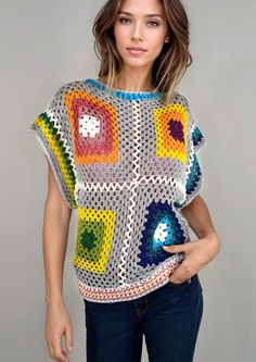 a woman wearing a colorful crochet sweater posing in front of a gray background