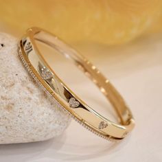 There are so many ways to love this fresh and fun cubic zirconia bangle bracelet. This darling bangle features heart designs made with CZ stones which adorns a band on one side. A meaningful look for the one you adore. - Stones Material: Cubic Zirconia. - Stones Shape: Round. - Metal: Brass. - Plating: 18k Gold plated. - Interior Diameter: 60 mm. - Width: Aprox. 5 mm. - Clasp: Snap Closure. - Circumference Inches: 7.42 Ships in a Balara Gift Pouch. Available in Gold. SKU# B1683 Gold Kada Design For Women Stylish, Gold Band Bracelet For Women, Indian Gold Bracelet For Women, Ladies Bangle Design, Bracelet Bangles For Women, Bangle Gold Designs, Gold Bracelet For Women Design, Gold Kada Design For Women Indian, Cubic Zirconia Bangle For Valentine's Day