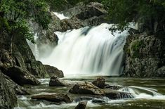 there is a waterfall in the middle of some rocks and water flowing down it's sides