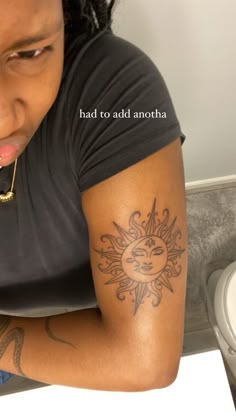 a woman with a sun tattoo on her arm looking down at the floor next to a toilet