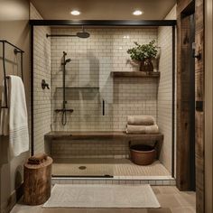 a walk in shower sitting next to a wooden shelf filled with towels and a potted plant