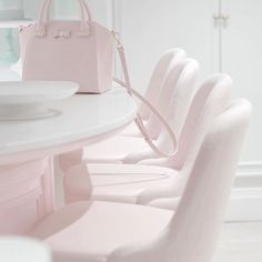 the chairs are all lined up at the white table with pink handbags on it