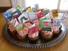 cupcakes with pink frosting and cards on them are sitting in a plate