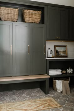 a bathroom with gray cabinets and baskets on the top shelf, next to a white toilet