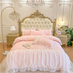 a bed with pink comforter and pillows in a room next to a chandelier