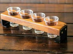 four shot glasses sitting on top of a wooden holder