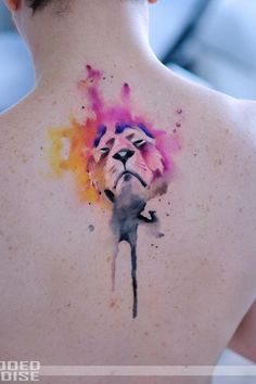 the back of a woman's neck with a watercolor tattoo on it, depicting a lion