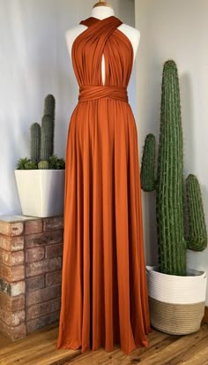 an orange dress sitting on top of a wooden floor next to cacti and succulents