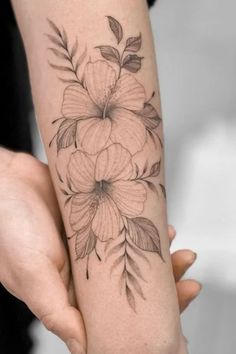 a woman's arm with flowers on it and leaves in the middle of her arm