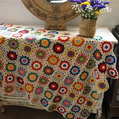 a crocheted tablecloth with flowers on it and a mirror in the background