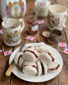 a white plate topped with pastries on top of a wooden table next to cups and saucers