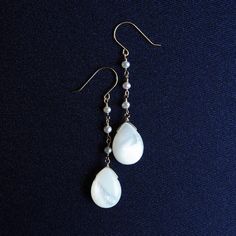 Long earrings made of white pearl and pearl - Perrine Perrine 【 Korintohs 】 This series of shell necklaces and earrings features beautiful Corinthian acanthus plant patterns inspired by the decorations of Greek temples. Light-reflecting white stones and black shadows, elegant decoration and rational structure, magnificent construction and a design that embraces light and wind. The characteristics of ancient Greek temples have been sublimated into summer jewelry. These long earrings are made from chains carefully spun from the smallest, most precious freshwater pearls on the market, which are difficult to cultivate, and feature white mother of pearl at the ends, giving them a delicate and elegant charm. The design, which resembles a single drop of water on the surface of the water, gives a White Pearl Pendant Earrings In Mother Of Pearl, White Pearl Charm Earrings, Pearl White Drop Earrings Made Of Mother Of Pearl, Formal Dangle Pearl Earrings In Mother Of Pearl, Pearl White Drop Earrings In Mother Of Pearl, Formal Mother Of Pearl Dangle Earrings, Elegant Mother Of Pearl Jewelry In Pearl White, White Teardrop Mother Of Pearl Jewelry, Delicate White Mother Of Pearl Jewelry