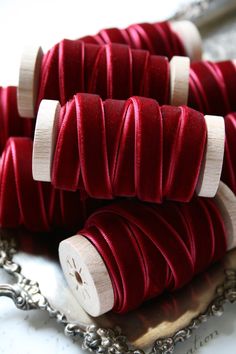 several red spools of thread sitting on top of a silver tray next to a chain