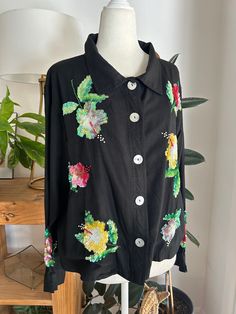 Beautiful, black cotton or rayon blouse with sequined hibiscus flowers. Blouse buttons down the front with big mother of perl buttons. In overall good vintage condition, with no major flaws, no holes, snags, smells, or missing sequins. The label has been removed, would guess is a modern size  M/L. Measurements  Chest 44in/111.5cm Length 22.5in/57cm Shoulder 19.5in/47cm Sleeve 22in/56cm Follow us on Instagram @LMVHOME https://www.Instagram.com/LMVHOME *Please read all policies on this and our pol Luxury Black Blouse With Floral Embroidery, Black Button-up Blouse With Floral Embroidery, Black Floral Embroidery Button-up Blouse, Sequin Flowers, Rayon Blouse, Hibiscus Flowers, Black Blouse, Black Cotton, Womens Clothing Tops