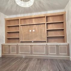 an empty room with built in bookshelves and cabinets