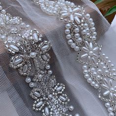 some white beads and pearls on a sheer fabric