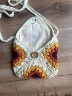 a crocheted purse sitting on top of a wooden floor next to a string