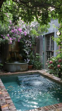 an outdoor swimming pool surrounded by greenery and potted plants with water running through it