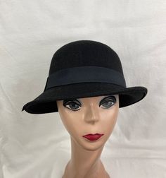 This vintage-inspired Black 1920s style wool felt cloche hat has a slanted downturned brim that is 2 inches and a black grosgrain ribbon band. The material is wool felt blended with acrylic fabric and the hat is lightweight and comfortable to wear. The inside band has an elastic sizing cord to adjust to your head size and will fit up to 22.5-inch heads. Classic Wool Cloche Hat With Curved Brim, Classic Adjustable Felt Cloche Hat, Adjustable Felt Cloche Hat In Classic Style, Adjustable Classic Felt Cloche Hat, Classic Cloche Felt Hat For Winter, Classic Winter Cloche Felt Hat, Classic Wool Cloche Fedora, Retro Fitted Brimmed Felt Hat, Fitted Fur Felt Cloche Hat With Flat Brim