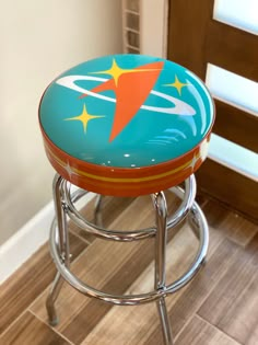 an orange and blue stool sitting on top of a wooden floor