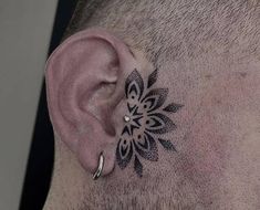 a close up of a man's ear with an intricate tattoo design on it