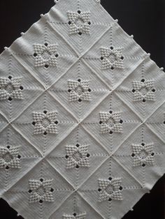 a white crocheted square with black dots on it