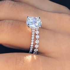 a woman's hand with a diamond ring on top of her finger and an engagement band