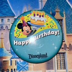 a mickey mouse birthday sign hanging from the side of a building with a castle in the background