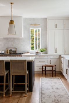 a large kitchen with white cabinets and wooden flooring, along with an area rug on the floor