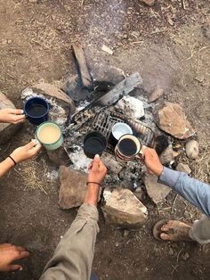 two people are toasting coffee over the campfire with their feet in the air