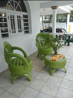 two green wicker chairs sitting next to each other on a tile floor in front of a house