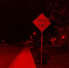 a red dead end sign sitting on the side of a road