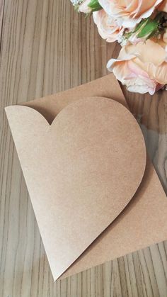 two pieces of brown paper sitting on top of a wooden table next to a bouquet of flowers