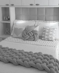 a large bed with pillows on top of it in a white and gray bedroom setting