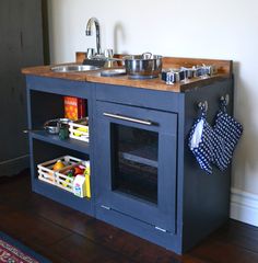 a blue play kitchen with sink, stove and pot holders on the wall above it