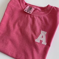 Best selling comfort colors tees paired with your little one's initial on the left chest. Made from 100% cotton, garment dyed, and super cozy! Your little one will make a statement in this tee! If you are wanting a different design, more wording, or a different clothing style, please send me a message so we can discuss the details. Varsity Style Cotton Tops With Embroidered Graphics, Cotton Varsity Tops With Embroidered Graphics, Cotton T-shirt With Letter Embroidery For College, Pink Embroidered Tops For College, Collegiate Cotton Tops With Embroidered Text, Collegiate Style Cotton Top With Embroidered Text, Sporty T-shirt With Embroidered Text For College, Graphic Tee With Letter Embroidery, Graphic Tee With Letter Embroidery Crew Neck