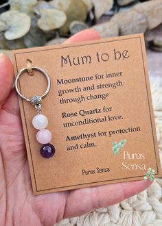 a person holding a keychain with a card attached to it that says mum to be